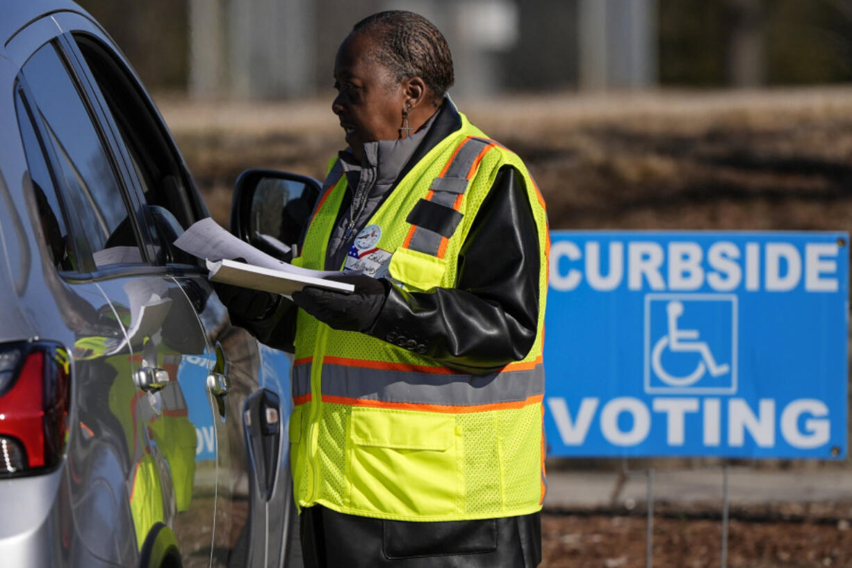 A voluntter election worker speaks with a voter during curbside early voting at the John Chavis Memorial Park Community Center, Wednesday, Feb. 21, 2024, in Raleigh, N.C.