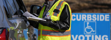 A voluntter election worker speaks with a voter during curbside early voting at the John Chavis Memorial Park Community Center, Wednesday, Feb. 21, 2024, in Raleigh, N.C.