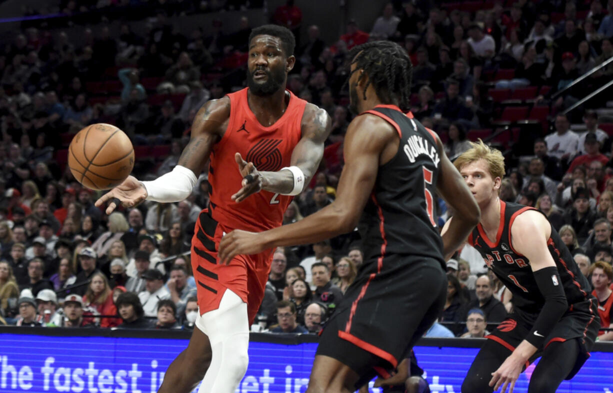 Portland Trail Blazers center Deandre Ayton, left, passes the ball as Toronto Raptors guard Immanuel Quickley, center, and guard Gradey Dick defend during the first half of an NBA basketball game in Portland, Ore., Saturday, March 9, 2024.