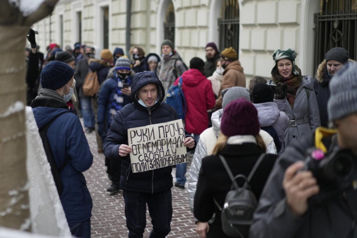 FILE - A demonstrator holds a poster saying, &ldquo;Hands off Memorial, freedom for political prisoners&rdquo; as people gather in front of the Russian Supreme Court in Moscow, Russia, on Tuesday, Dec. 14, 2021. The court ordered the closure of Memorial, one of the country&rsquo;s oldest and most prominent human rights organizations. It drew acclaim for highlighting repression in the Soviet Union and was awarded the 2022 Nobel Peace Prize for its work.