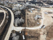 Electrical crews, bottom, replace burnt power poles near a destroyed residence, along the Canadian River in Canadian, Texas, Thursday, Feb. 29, 2024.