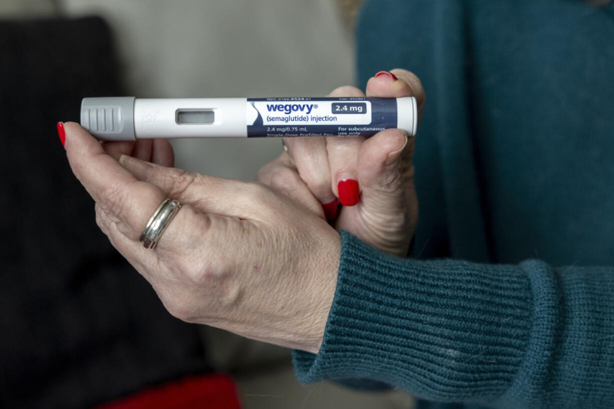 FILE - Donna Cooper holds up a dosage of Wegovy, a drug used for weight loss, at her home, March 1, 2024, in Front Royal, Va. The popular weight-loss drug Wegovy may be paid for by Medicare &mdash; as long as patients using it also have heart disease and need to reduce the risk of future heart attacks, strokes and other serious problems, federal officials said Thursday, March 21.