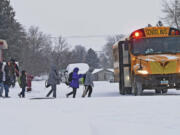 Children in winter coats line up to get into a school bus Thursday in Bismarck, N.D.