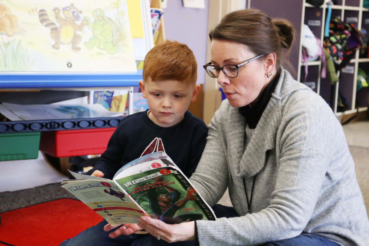 A 4-year-old student reads a book with a staff member during a Washougal School District Transition to Kindergarten class in 2024.