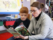 A 4-year-old student reads a book with a staff member during a Washougal School District Transition to Kindergarten class in 2024.