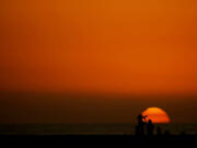 Beachgoers are framed against the setting sun at the end of a warm day Dec. 6 in Huntington Beach, Calif. Last year&rsquo;s global average temperature of 58.96 degrees was about a third of a degree warmer than the previous hottest year in 2016.