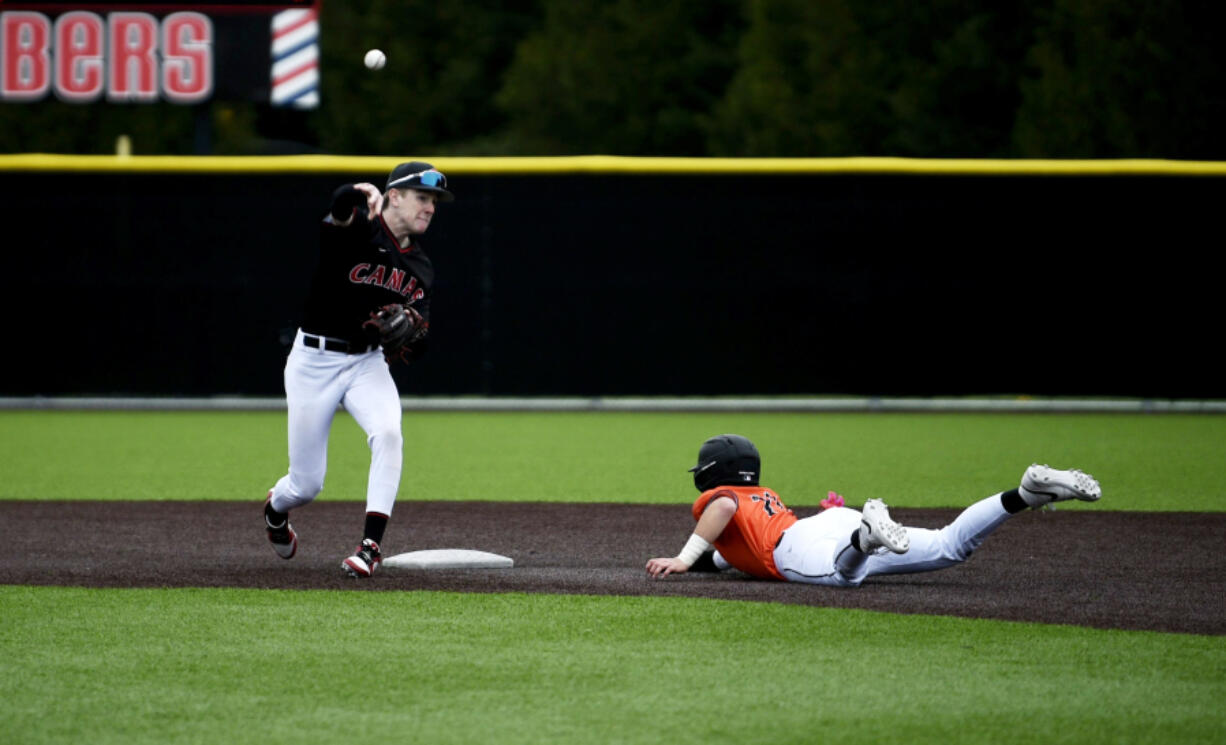 Camas second baseman Cade Lukens, left, throws to first for a double play after forcing out Battle Ground&#039;s Tyler Baldwin in a 4A Greater St. Helens League baseball game on Thursday, April 11, 2024 at Camas High School.