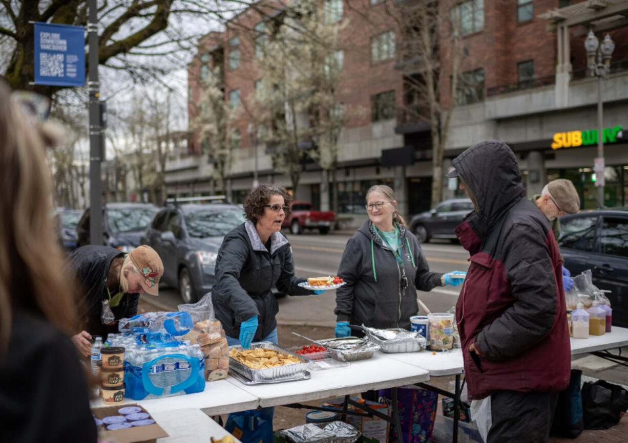 Free Hot Soup Vancouver volunteers Jennifer Wyld, from left, Becky Harrington and Ronda Hansen prepare a plate of food for a person at Esther Short Park in downtown Vancouver. The volunteers are part of a yearslong effort to help the hungry.