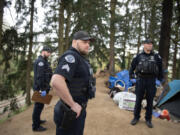 Vancouver police Patrol Sgt. Zachary Ripp, center, works with colleagues while responding to a call of a dead person at a homeless encampment Thursday afternoon near Hazel Dell. Five officers responded to the call, which combined with another call at the same time, tied up all the officers working on the west side of the city.