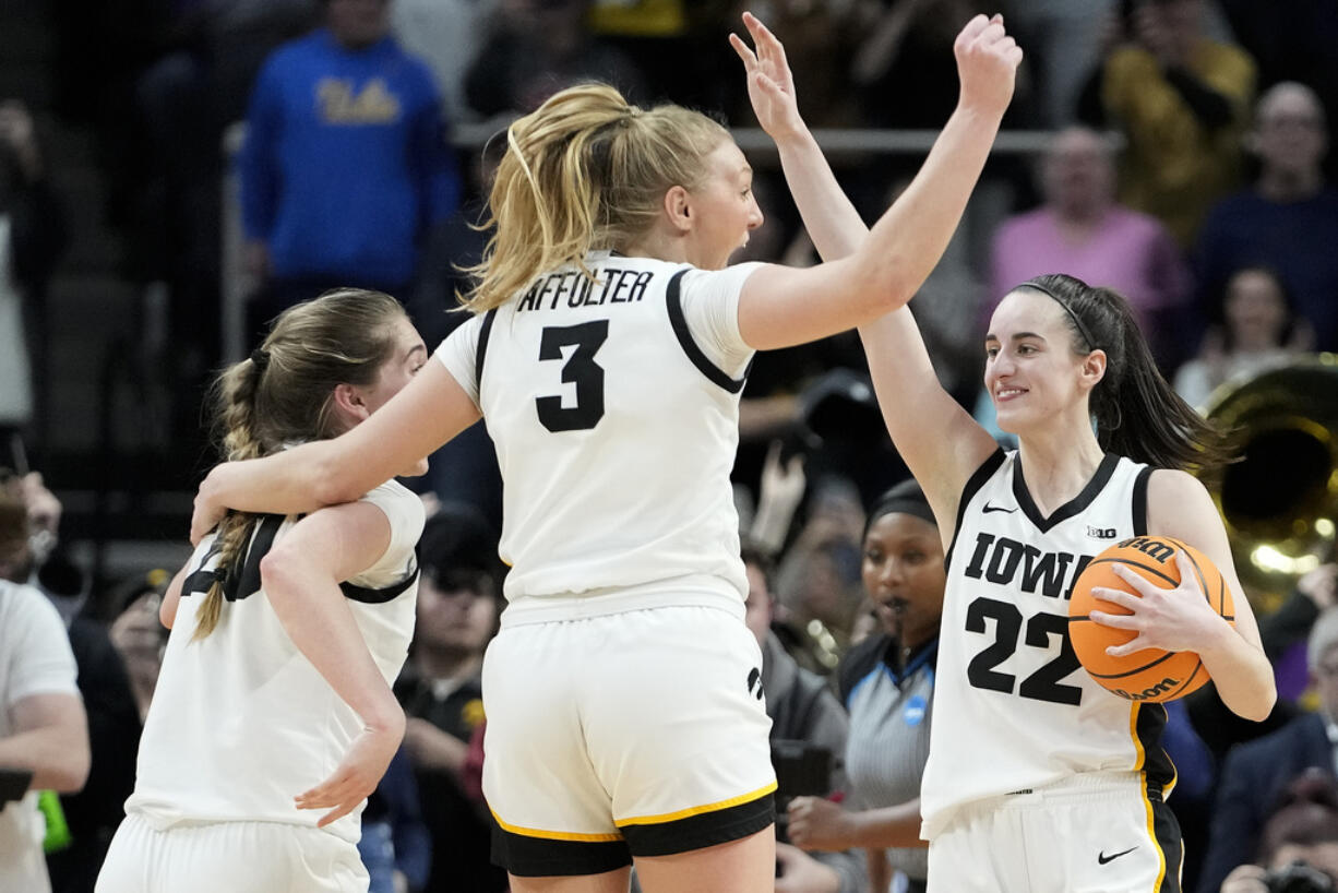 Iowa guard Caitlin Clark (22), guard Sydney Affolter (3) and guard Kate Martin (20) celebrate after defeating LSU in an Elite Eight round college basketball game during the NCAA Tournament, Monday, April 1, 2024, in Albany, N.Y.