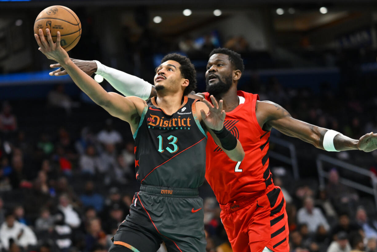 Washington Wizards guard Jordan Poole, left, drives past Portland Trail Blazers center Deandre Ayton for a basket during the first half of an NBA basketball game Friday, April 5, 2024, in Washington.