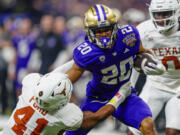 FILE - Texas linebacker Jaylan Ford (41) tries to tackle Washington running back Tylin "Tybo" Rogers (20) during the Sugar Bowl CFP NCAA semifinal college football game, Jan. 1, 2024, in New Orleans. Rogers was arrested Friday, April 5, and charged Tuesday, April 9, with raping two women in Seattle. Court documents say he played in two College Football Playoff games for the school after the allegations were known to the university.