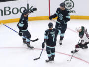 Seattle Kraken center Shane Wright, top right, celebrates his goal with Justin Schultz (4) and Jordan Eberle (7) as Arizona Coyotes defenseman J.J. Moser, right, skates away during the first period of an NHL hockey game Tuesday, April 9, 2024, in Seattle.