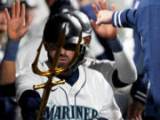 Seattle Mariners' Mitch Haniger points a trident in the dugout after hitting a two-run home run against the Cincinnati Reds during the third inning of a baseball game Monday, April 15, 2024, in Seattle.