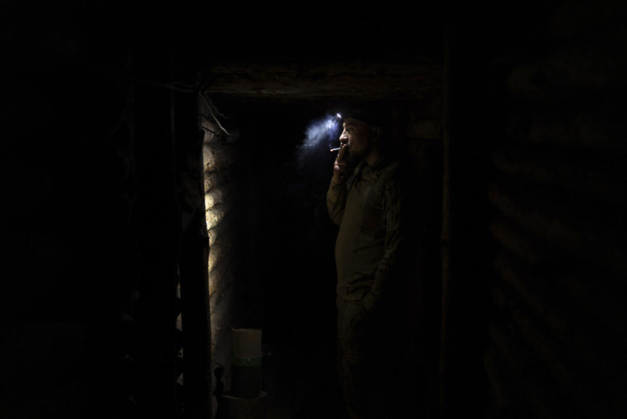 A Ukrainian serviceman from the Azov brigade, known by the call sign Yenot, smokes a cigarette in trenches around one kilometer away from Russian forces on the frontline in Kreminna direction, Donetsk region, Ukraine, Friday, April 12, 2024.