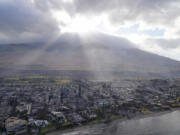 FILE - The sun shines through clouds over wildfire wreckage in Lahaina, Hawaii, Aug. 10, 2023. A dangerous mix of conditions appear to have combined to make the wildfires blazing a path of destruction in Hawaii particularly damaging, including flash drought, high winds, low humidity and dry vegetation. According to a new poll, Asian Americans, Native Hawaiians and Pacific Islanders in the United States are slightly more likely than the overall adult population to believe in human-caused climate change. The recent poll from AAPI Data and The Associated Press-NORC Center for Public Affairs Research finds 84% of AAPI adults agree climate change exists. In comparison, 74% of all U.S. adults hold the same sentiment.