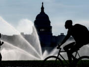 FILE - The Capitol is seen as water sprinklers soak the National Mall on a hot summer morning in Washington, July 15, 2022. A new poll finds that most Americans share many core values on what it means to be an American despite the country&rsquo;s deep political polarization. The poll from The Associated Press-NORC Center for Public Affairs Research found that about 9 in 10 U.S. adults say the right to vote, the right to equal protection under the law and the right to privacy are important or very important to the U.S.&rsquo;s identity as a nation.(AP Photo/J.