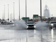 An SUV splashes through standing water on a road with the Burj Al Arab luxury hotel seen in the background in Dubai, United Arab Emirates, Tuesday, April 16, 2024. Heavy rains lashed the United Arab Emirates on Tuesday, flooding out portions of major highways and leaving vehicles abandoned on roadways across Dubai. Meanwhile, the death toll in separate heavy flooding in neighboring Oman rose to 18 with others still missing as the sultanate prepared for the storm.