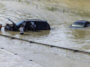 A group of people work to recover an abandoned vehicle taken by floodwater caused by heavy rain in Dubai, United Arab Emirates, Thursday, April 18, 2024. The United Arab Emirates attempted to dry out Thursday from the heaviest rain the desert nation has ever recorded, a deluge that flooded out Dubai International Airport and disrupted flights through the world&rsquo;s busiest airfield for international travel.