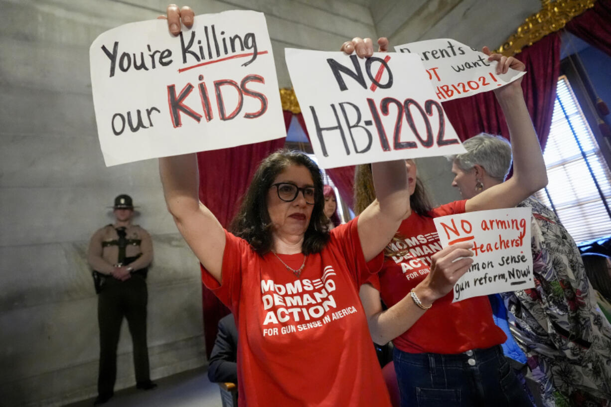 Anna Fahrenholz holds signs in the gallery against a bill that would allow some teachers to be armed in schools during a legislative session in the House chamber Tuesday, April 23, 2024, in Nashville, Tenn.