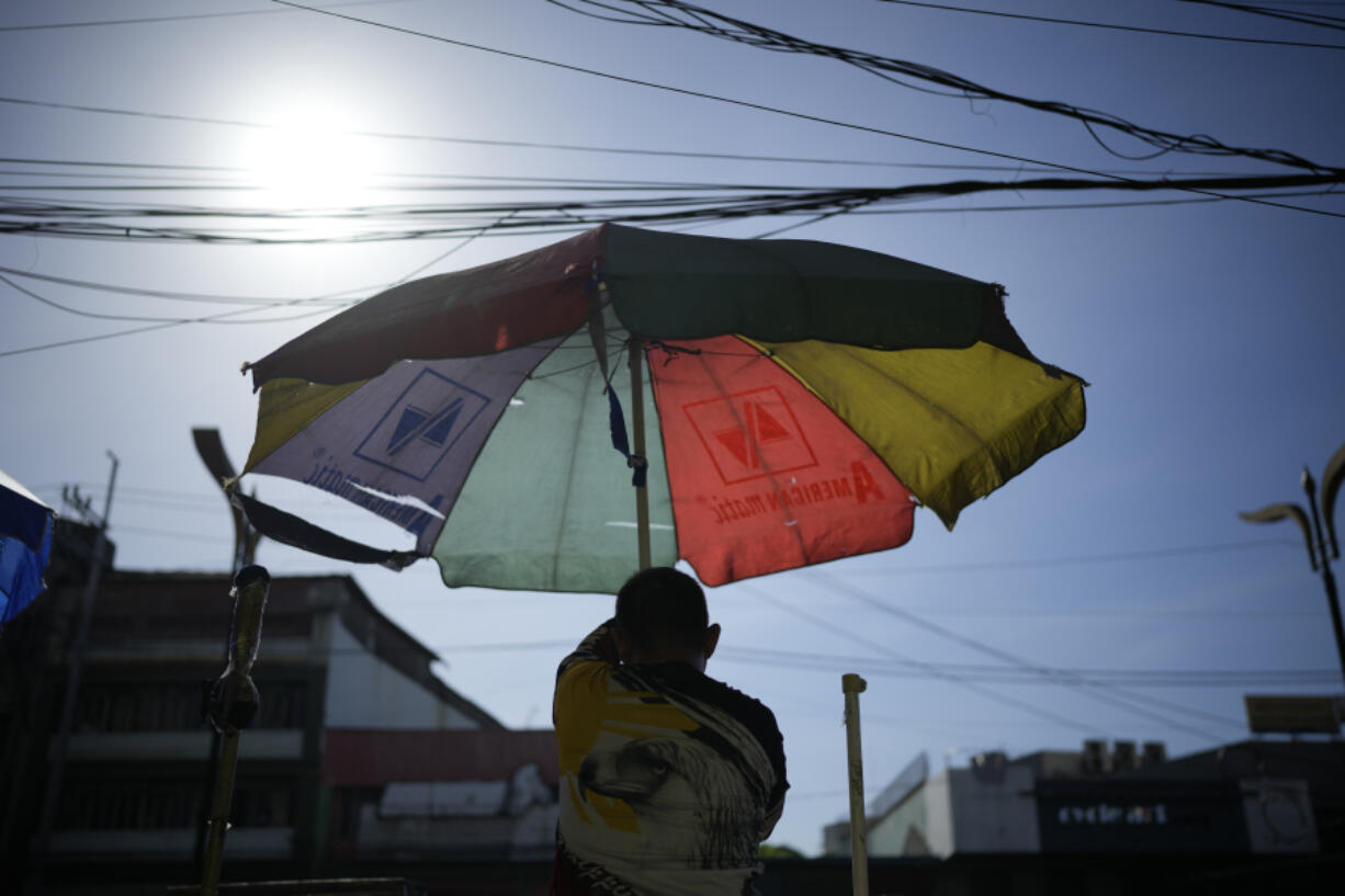 A vendor prepares his umbrella as hot days continue in Manila, Philippines on Monday, April 29, 2024. Millions of students in all public schools across the Philippines were ordered to stay home Monday after authorities cancelled in-person classes for two days as an emergency step due to the scorching heat and a public transport strike.