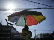 A vendor prepares his umbrella as hot days continue in Manila, Philippines on Monday, April 29, 2024. Millions of students in all public schools across the Philippines were ordered to stay home Monday after authorities cancelled in-person classes for two days as an emergency step due to the scorching heat and a public transport strike.