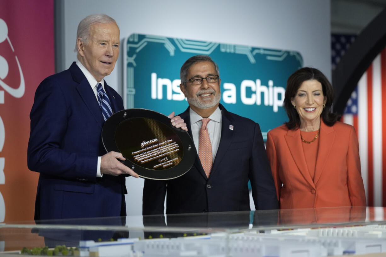 Micron Technology CEO Sanjay Mehrotra, center, presents a plaque to President Joe Biden, left, in honor of Biden&rsquo;s support of Micron through the CHIPS and Science Act, at the Milton J. Rubenstein Museum, Thursday, April 25, 2024, in Syracuse, N.Y. Pictured at right is New York Governor Kathy Hochul.