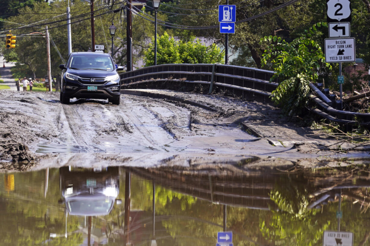 FILE - A driver stops on a mud-covered bridge while deciding whether to drive through flood waters of the Winooski River, July 12, 2023, in Montpelier, Vt. The Biden administration on Thursday, April 11, 2024, awarded $830 million in grants to fund 80 projects aimed at toughening the nation&rsquo;s aging infrastructure against the harmful impacts of climate change.