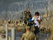 FILE - Migrants are taken into custody by officials at the Texas-Mexico border, Jan. 3, 2024, in Eagle Pass, Texas.