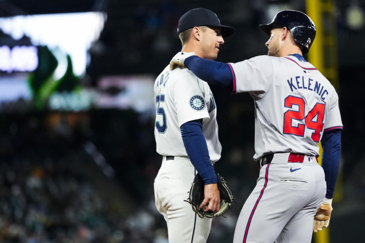 Seattle Mariners shortstop Dylan Moore, left, talks with Atlanta Braves&rsquo; Jarred Kelenic, right, as they wait for a video review on whether Kelenic was out at first base during the third inning of a baseball game Monday, April 29, 2024, in Seattle.