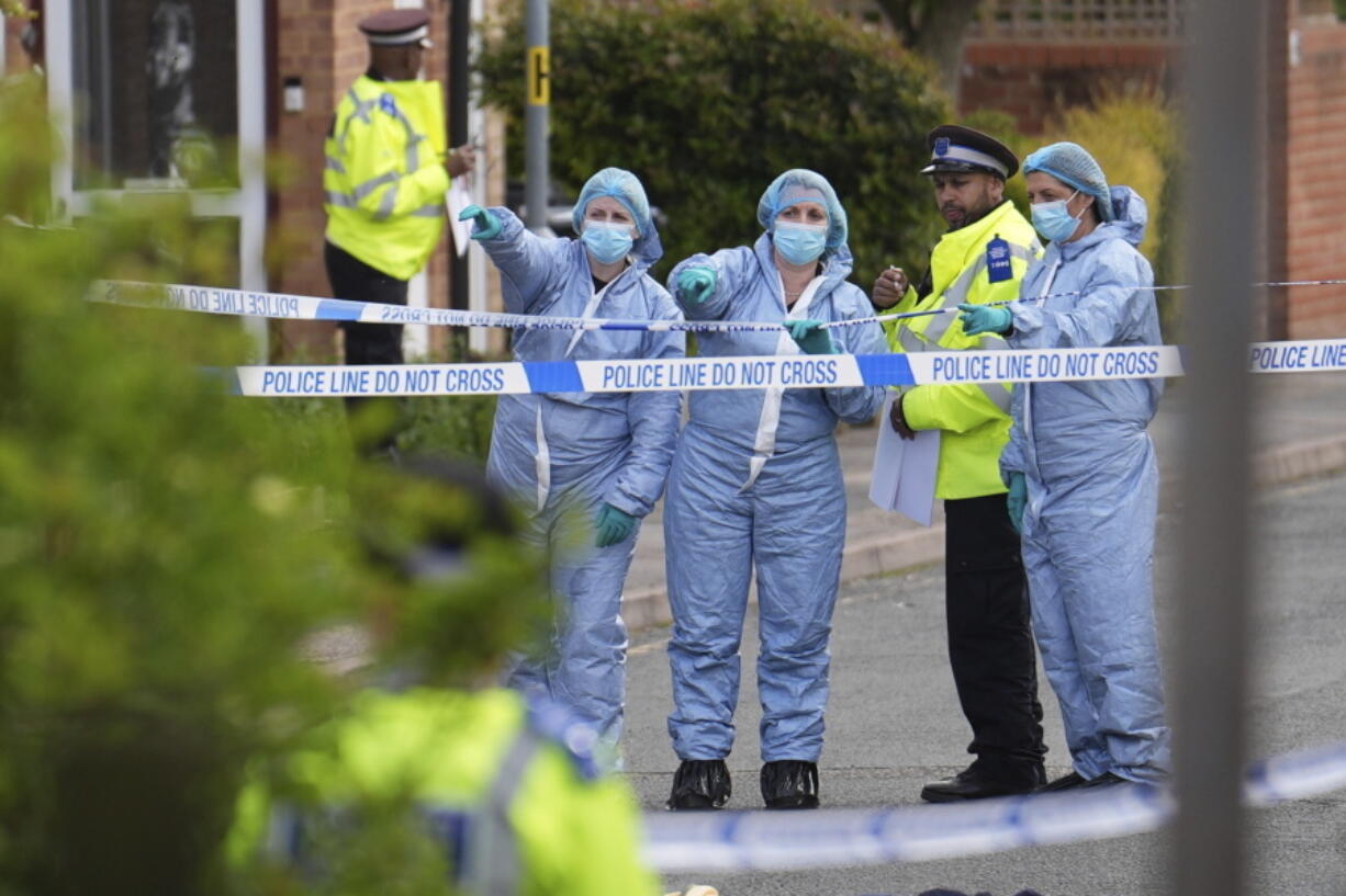 Forensics officers gesture near the scene of an attack in Hainault, north east London, Tuesday April 30, 2024. A man wielding a sword attacked members of the public and police officers in a east London suburb, killing a 13-year-old boy and injuring four others, authorities said Tuesday. The man was arrested at the scene, police said. Chief Supt.