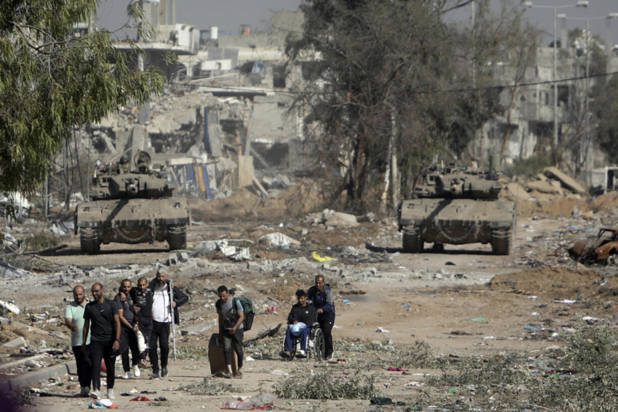 CORRECTS DIRECTION TO FLEE FROM - FILE - Palestinians flee from northern Gaza as Israeli tanks block the Salah al-Din road in the central Gaza Strip on Nov. 24, 2023, as the four-day cease-fire in the Israel-Hamas war begins as part of an agreement that Qatar helped broker.