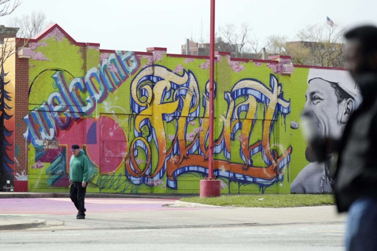 People walk by a mural in downtown Flint, Mich., Monday, March 25, 2024.