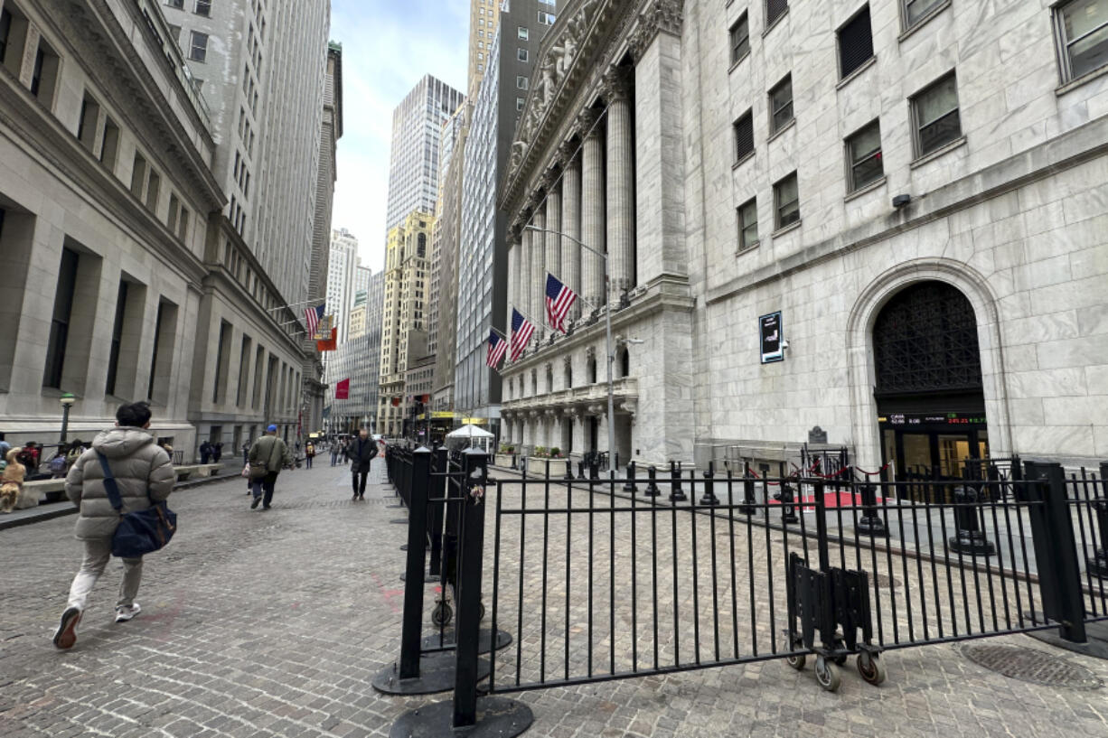 People pass the New York Stock Exchange, right, on Wednesday, April 17, 2024 in New York. Global shares are trading mixed after most U.S.