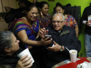 Cristel Cordona, second from left, shows photos of a recent marriage to visiting Guatemalan Cardinal Alvaro Ramazzini, at the St. Anne Catholic Church, in Carthage, Miss., Dec. 20, 2019. Ramazzini was at the parish to participate in a listening session with immigrants impacted by arrests by immigration agents at seven Mississippi food processing plants. (AP Photo/Rogelio V.