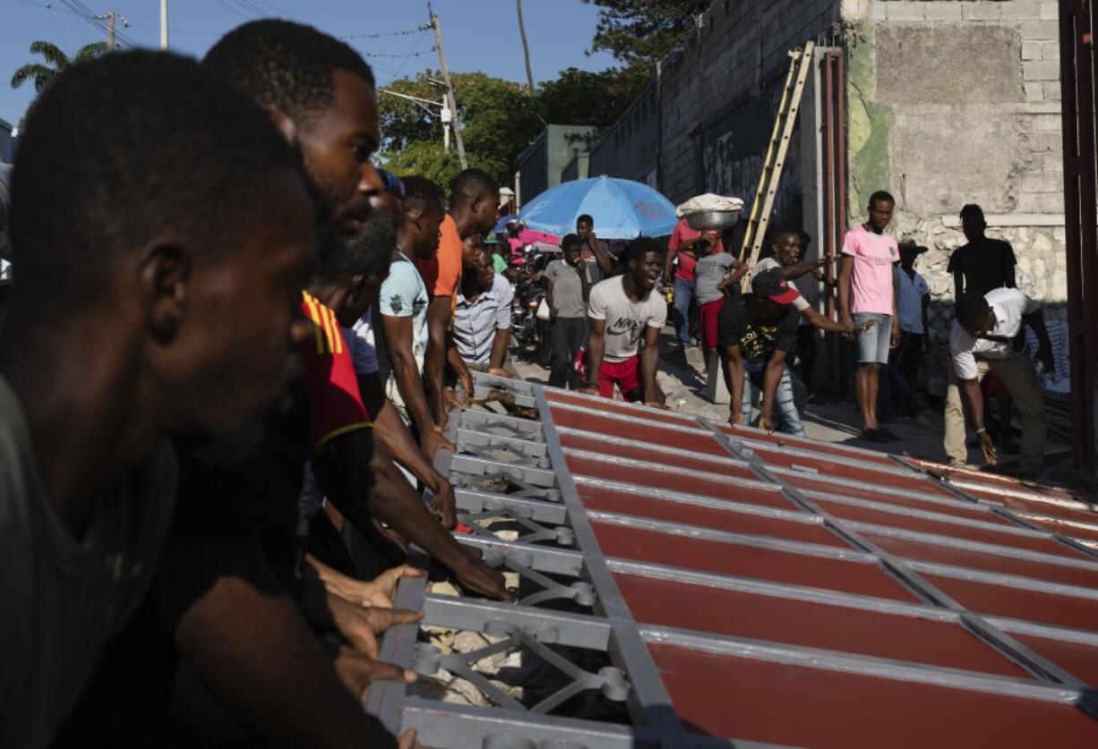 Neighbors raise a metal gate as they work to install it as a barricade against gangs, in the Petion-Ville neighborhood of Port-au-Prince, Haiti, Saturday, April 20, 2024.