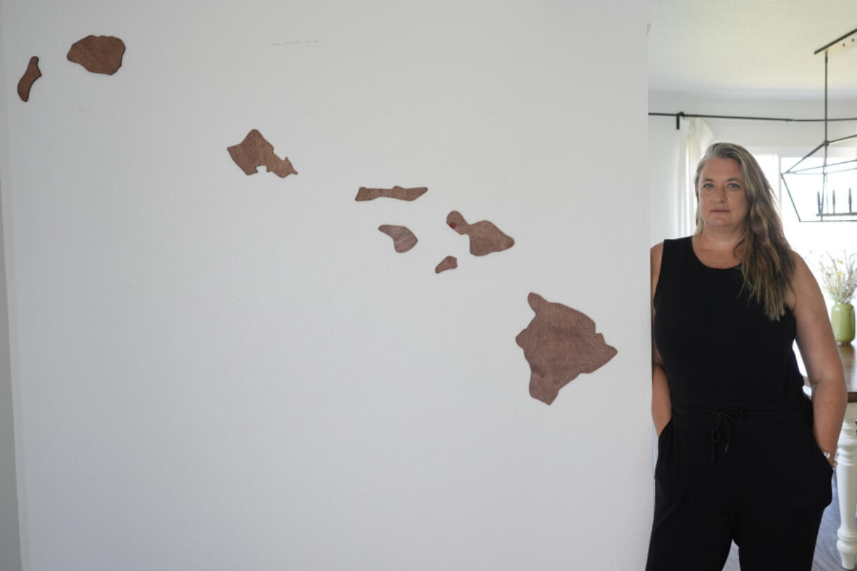 Amy Chadwick, stands by map of Hawaii at her current home Monday, April 8, 2024, in Satellite Beach, Fla. Chadwick, a victim of the fires in Hawaii moved to Florida where she could stretch her homeowners insurance dollars while she waits for her lot to be cleared and for permission to rebuild.