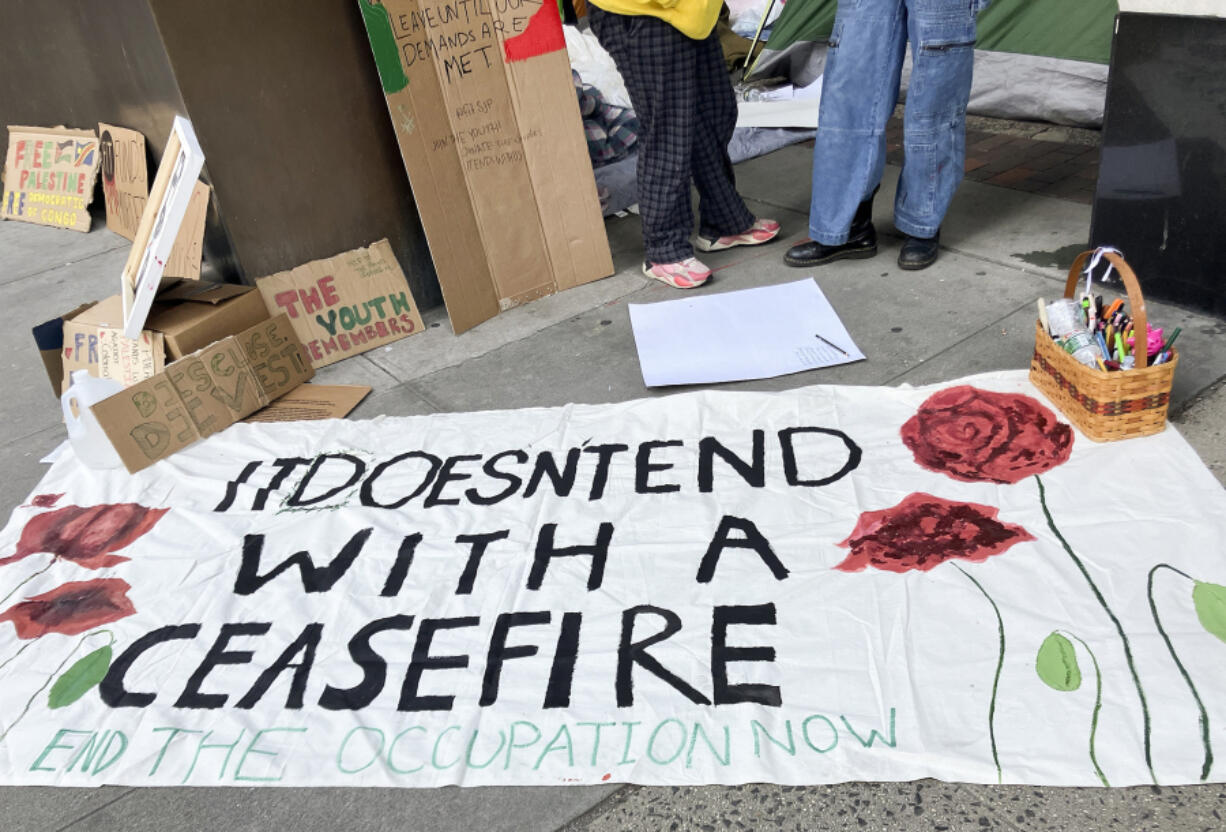 Protesters lay a banner on the sidewalk outside the Fashion Institute of Technology, Friday, April 26, 2024, in New York. As the death toll mounts in the war in Gaza and the humanitarian crisis worsens, protesters at universities across the country are demanding schools cut financial ties to Israel and divest from companies they say are enabling the conflict.