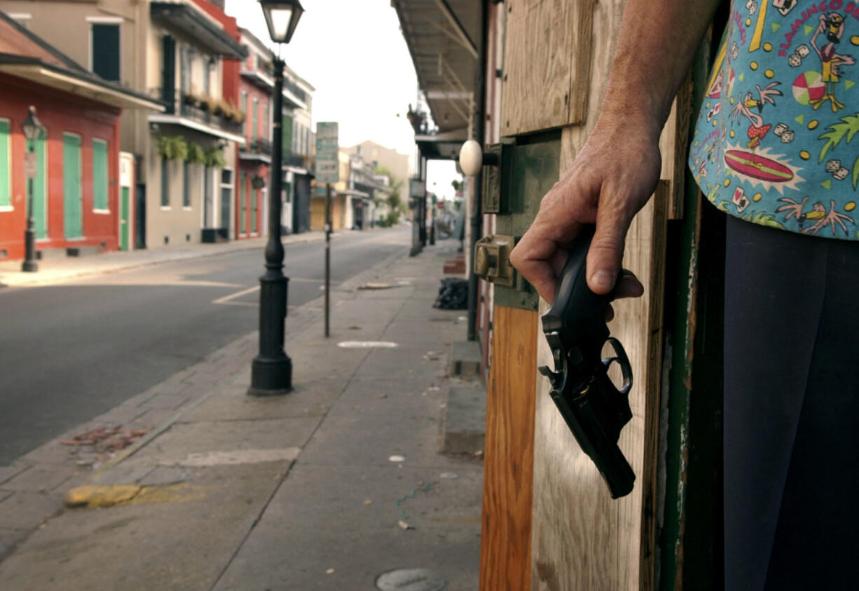 FILE - A New Orleans French Quarter resident holds a handgun as he keeps watch on his house on Bourbon Street, Sept. 12, 2005. As Louisiana prepares for a new law to go into effect that allows those 18 and older to carry a concealed handgun without a permit, a Republican-controlled committee pushed back against bills Wednesday, April 17, 2024, that seek to restrict where people can carry guns.