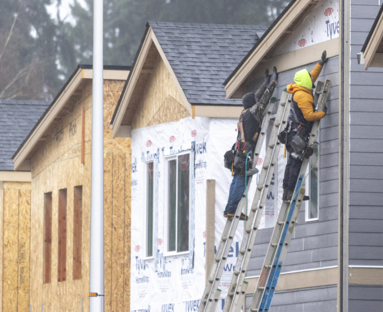 Construction workers hold a piece of siding in place while building houses along Northeast 138th Avenue in east Vancouver.