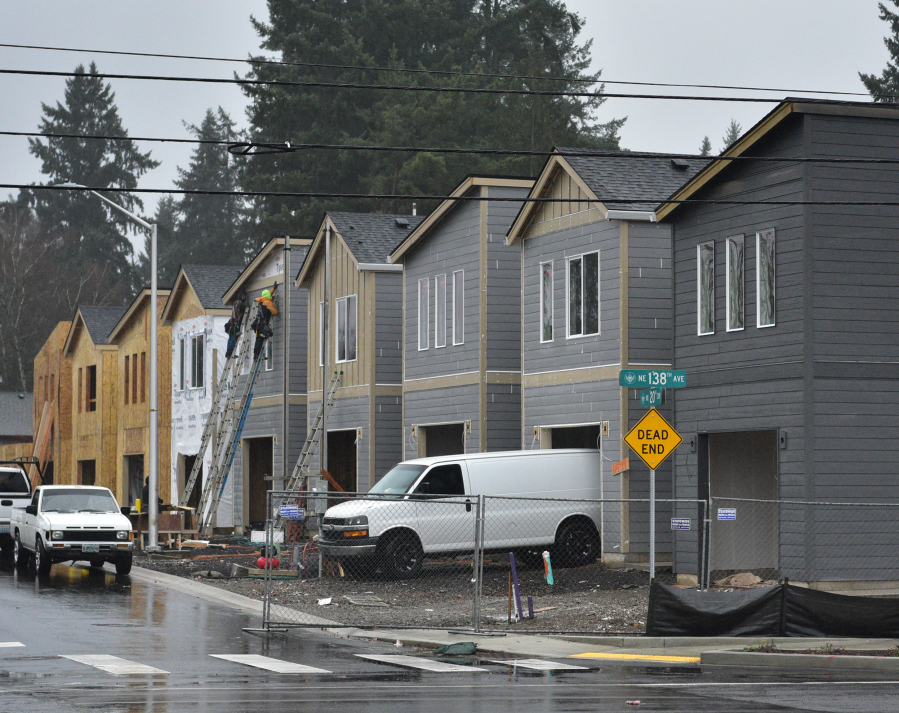Construction workers hold a piece of siding in place while building houses along Northeast 138th Avenue in east Vancouver.