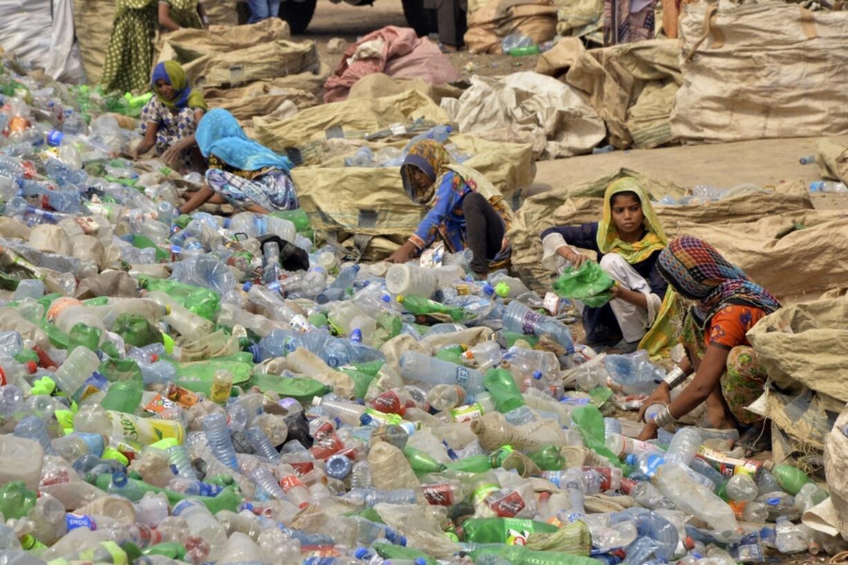 FILE - Pakistani laborers, mostly women, sort through empty bottles at a plastic recycling factory in Hyderabad, Pakistan, April 30, 2023.