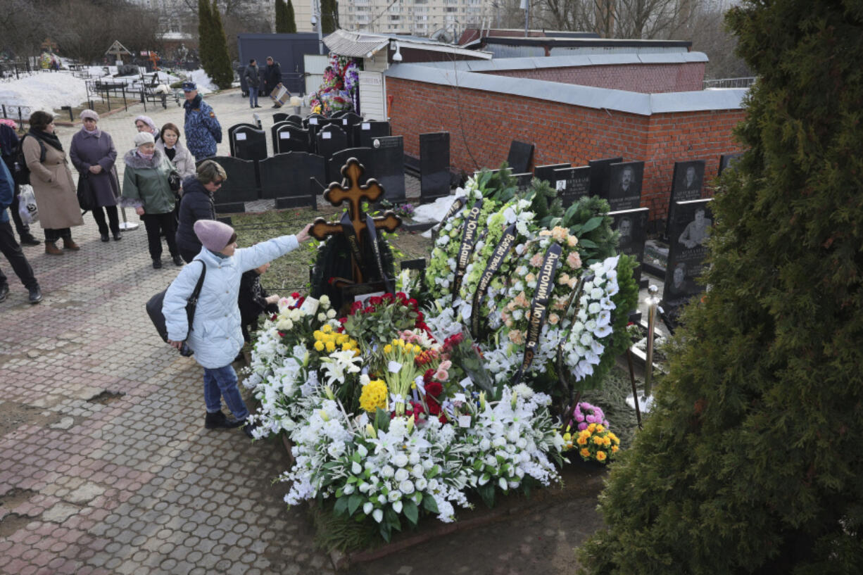 A woman touches a cross at the grave of Russian opposition leader Alexei Navalny on the fortieth day after his death as per Orthodox tradition at the Borisovskoye Cemetery, in Moscow, Russia, Tuesday, March 26, 2024.