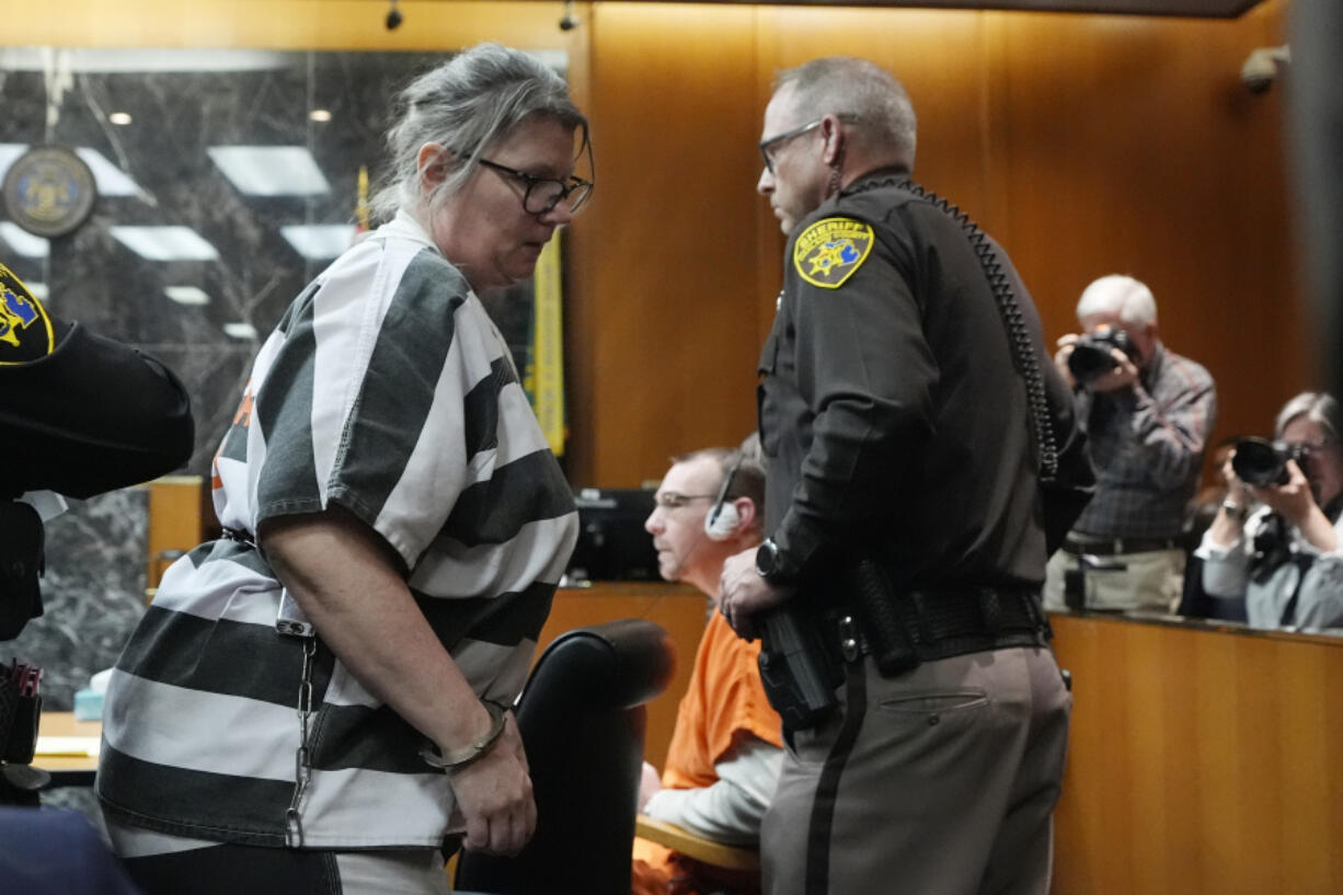 Jennifer Crumbley, walks by her husband James Crumbley, seated, as she is escorted out of court after their sentencing, Tuesday, April 9, 2024, in Pontiac, Mich.  The Crumbleys, the parents of a Michigan school shooter, were sentenced to at least 10 years in prison Tuesday for failing to take steps that could have prevented the killing of four students in 2021.