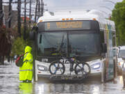 People stand in floodwaters as they try to get on a city bus during severe weather in New Orleans, on Wednesday, April 10, 2024.