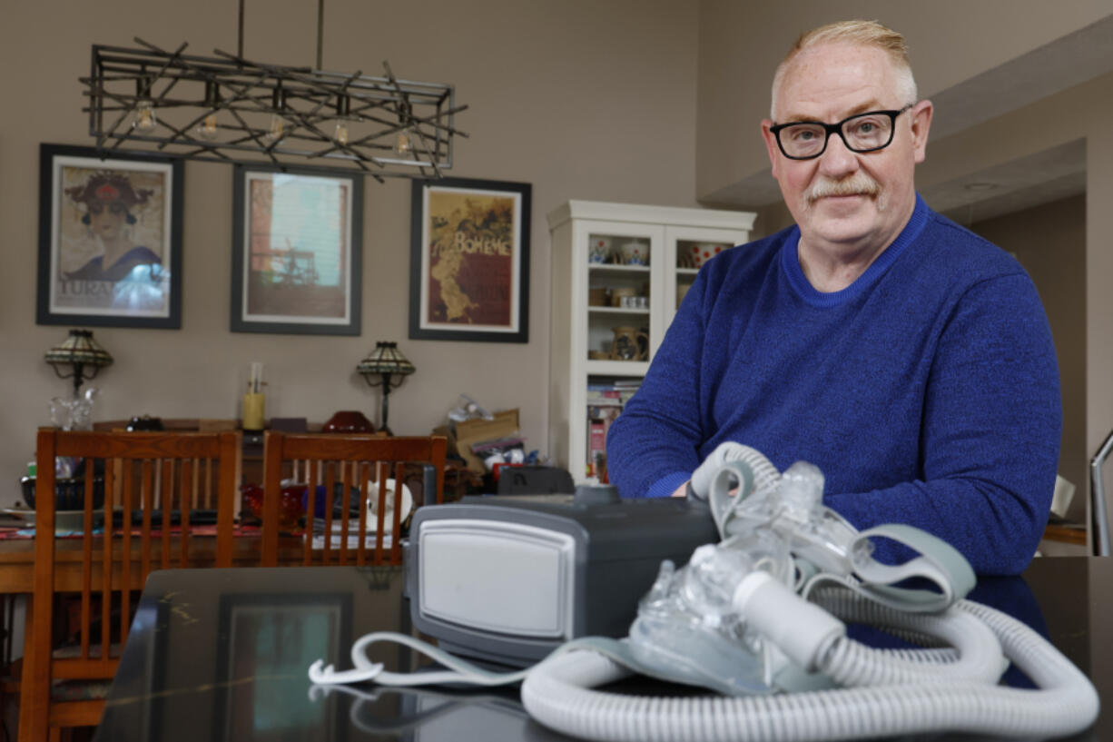 FILE - Jeffrey Reed, who experienced persistent sinus infections and two bouts of pneumonia while using a Philips CPAP machine, poses with the device at his home, Oct. 20, 2022, in Marysville, Ohio. The company responsible for a global recall of sleep apnea machines will be barred from resuming production at U.S. facilities until it meets a number of safety requirements under a long-awaited settlement announced Tuesday, April 9, 2024 by federal officials.