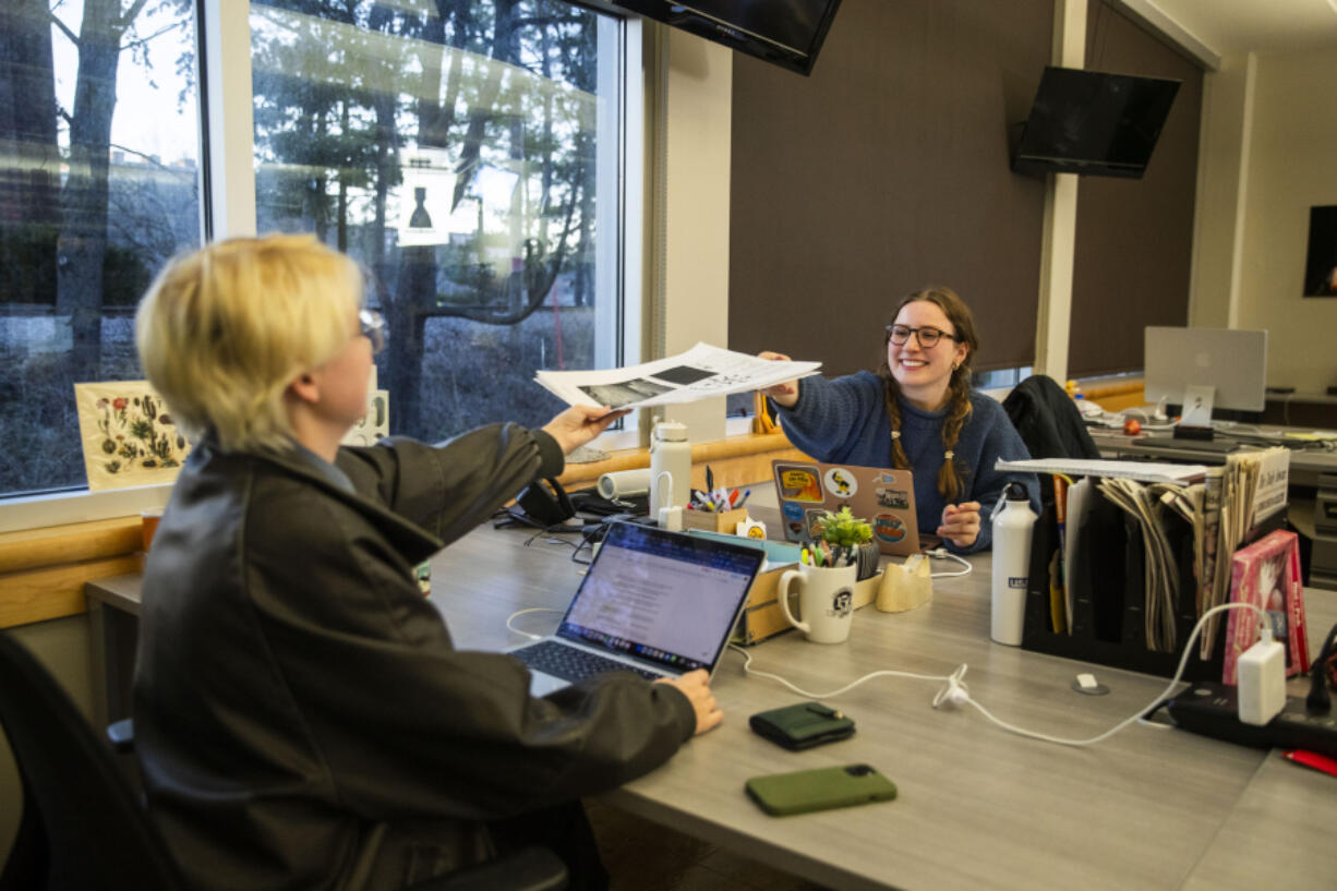 Executive Editor Sabine Martin, right, passes a drafted paper to Managing Editor Parker Jones in The Daily Iowan newsroom, Feb. 29, 2024, in Iowa City, Iowa.