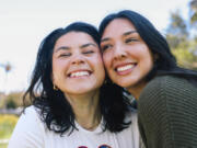 Friends Mary Delgado and Emmely Avila, left and right, pose for a portrait together where they first met at Echo Park Lake on Tuesday, April 16, 2024, in Los Angeles. Emmely is the founder and organizer of the Los Angeles Friends Club, a group designed to help people connect and she met her best friend Mary through the club.