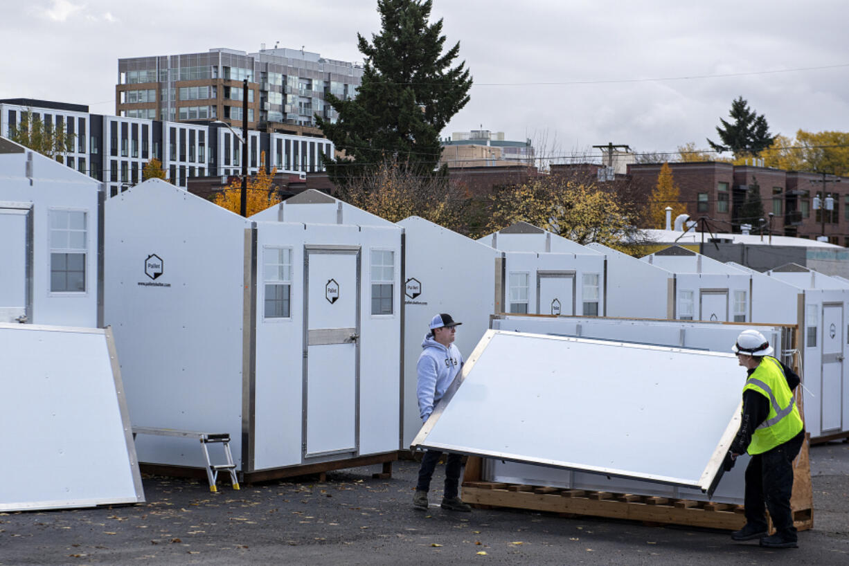 Andrew Reed of City Electric Co., left, helps Christian Trokey-Backman of Pallet unload roofs for the third Safe Stay community in downtown Vancouver on Nov. 7. The city approved an emergency declaration for homelessness Nov. 6.