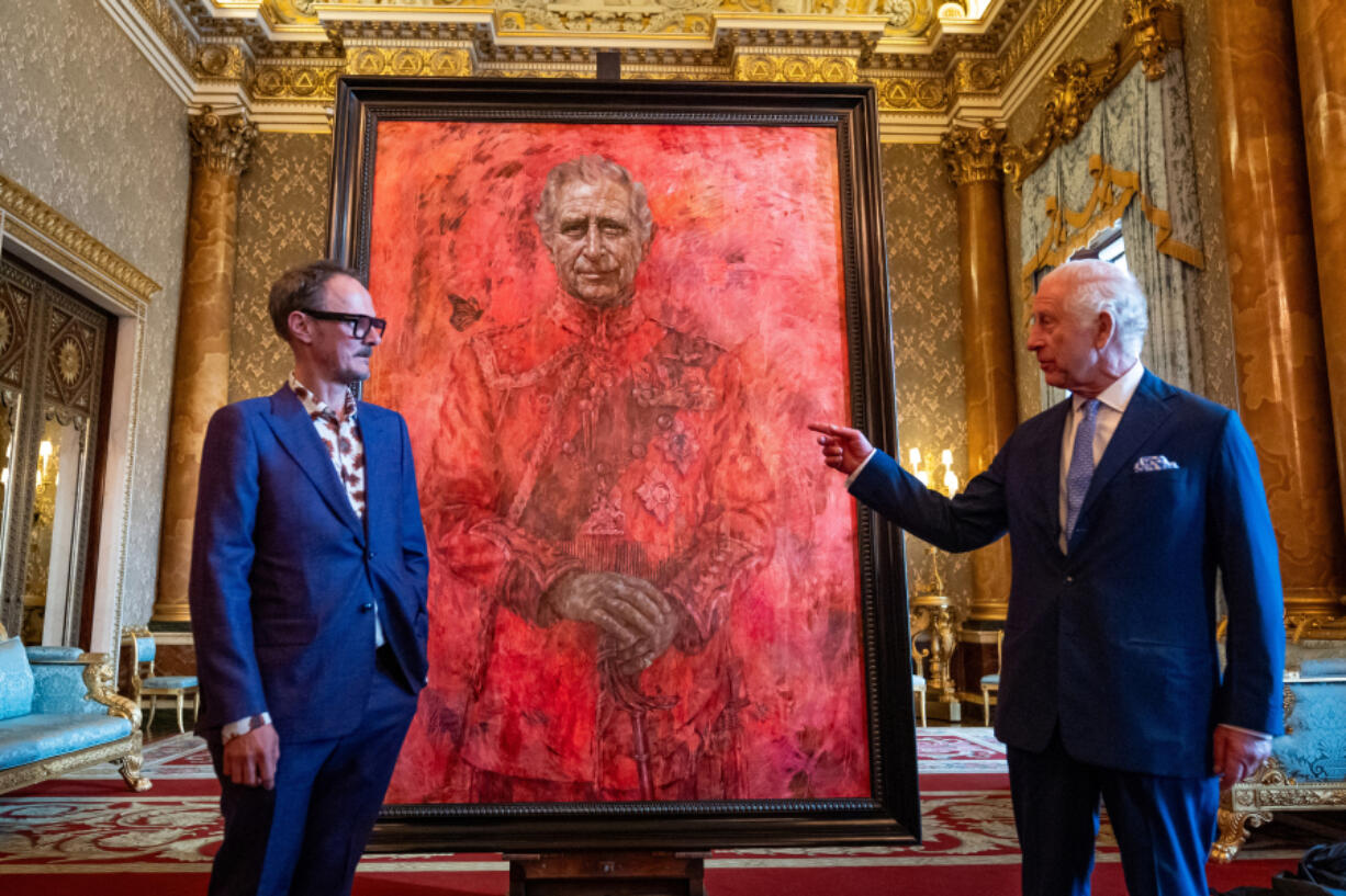 Artist Jonathan Yeo, left, and King Charles III stand in front of the artist&rsquo;s portrait of the king as it is unveiled in the blue drawing room at Buckingham Palace on Tuesday in London.